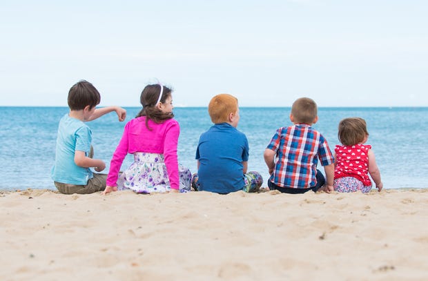 Five children sitting on the white sand of a Dorset beach